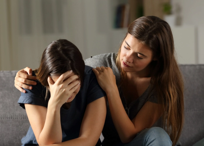 Woman comforting a distressed friend at home, offering emotional support.