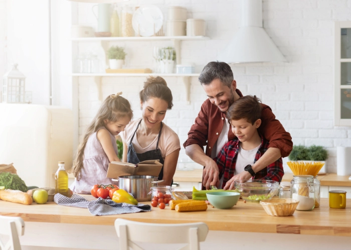 A smiling family preparing a meal together in a bright kitchen, symbolizing routine, planning, and shared responsibility — key elements in diabetes management and pre-bolusin