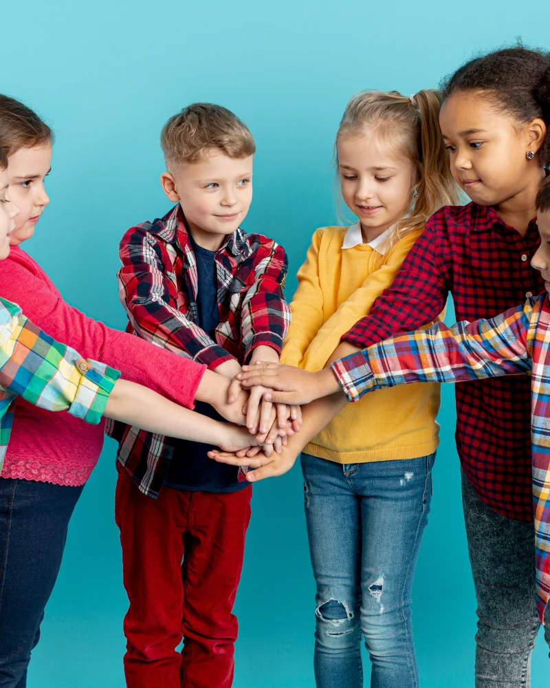 Group of children putting hands together in teamwork gesture