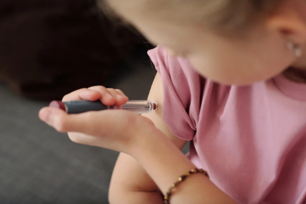 Child with type 1 diabetes injecting insulin with a pen.