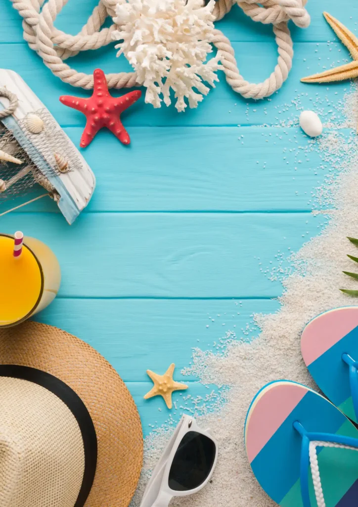Summer beach background with hat, sunglasses, flip-flops, and tropical drink on blue wooden table.