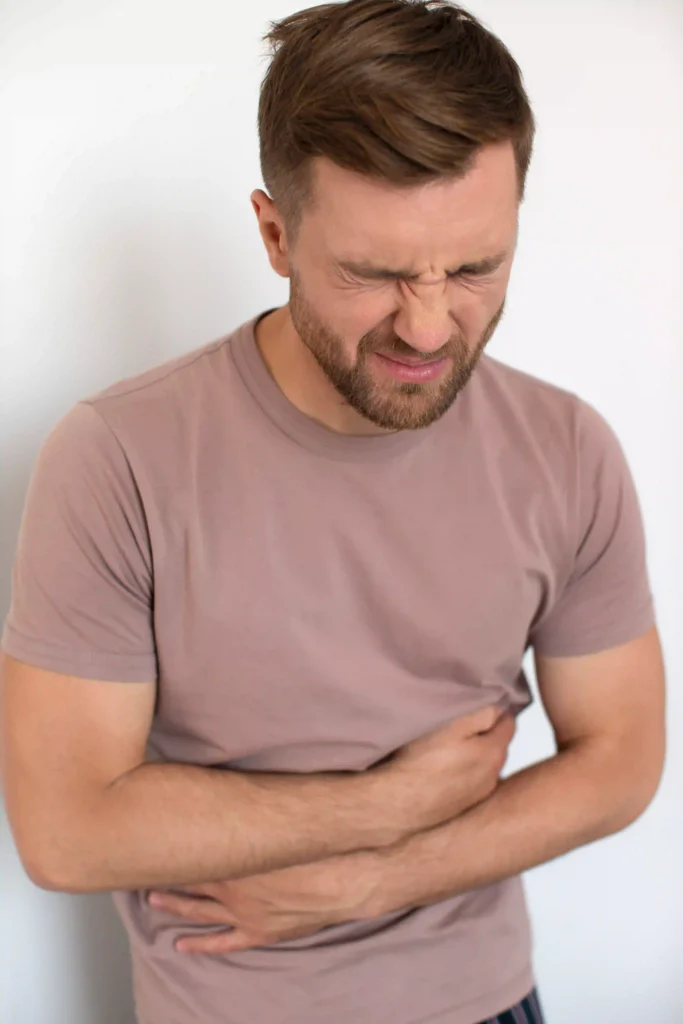 Man with stomach pain holding abdomen.